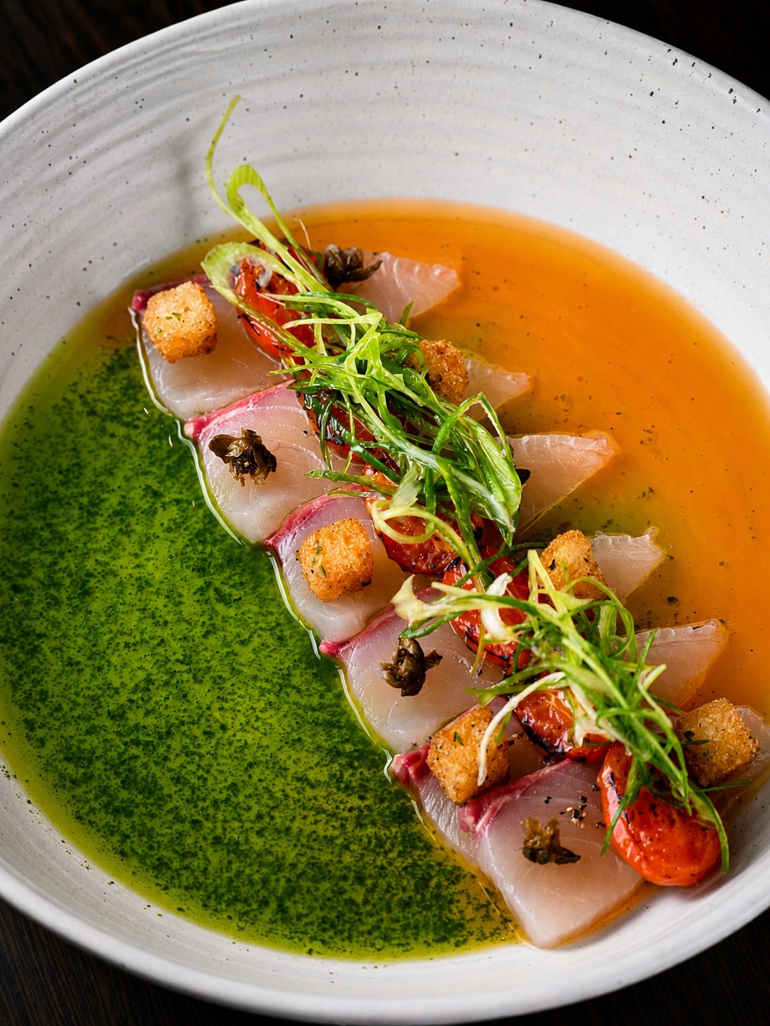 Sliced fish served with green and orange sauces