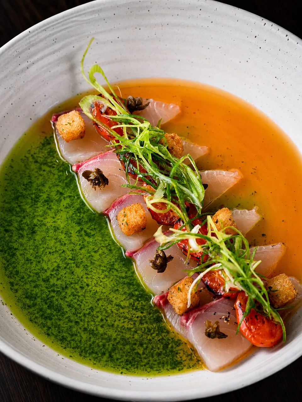 Sliced fish served with green and orange sauces